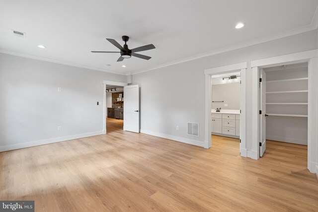 unfurnished bedroom featuring a spacious closet, a closet, crown molding, ceiling fan, and ensuite bathroom