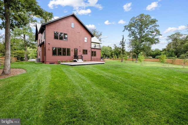 back of house featuring central AC unit, a deck, and a lawn