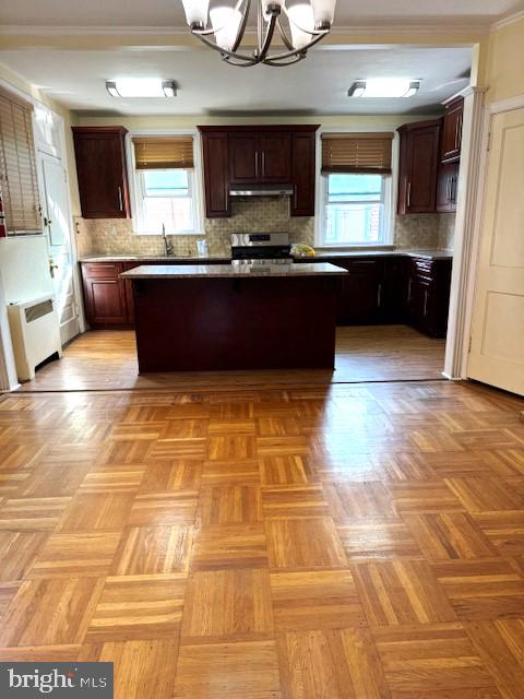 kitchen featuring a center island, decorative backsplash, and a notable chandelier