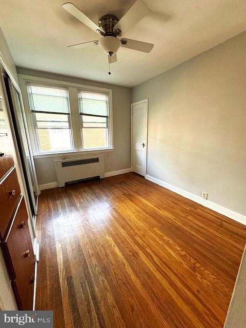 unfurnished room featuring ceiling fan, radiator heating unit, and wood-type flooring