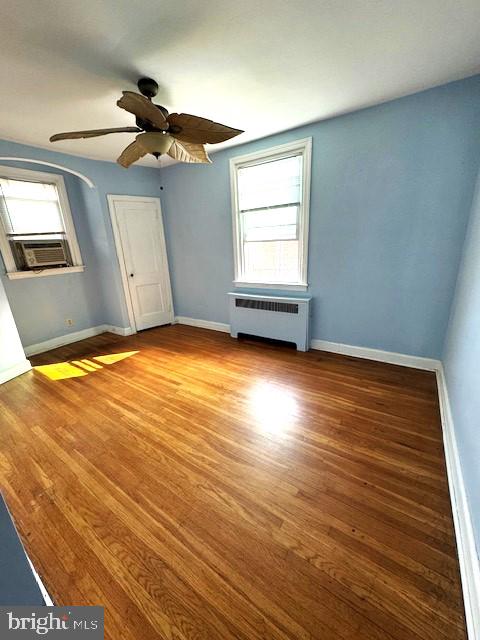 interior space with cooling unit, ceiling fan, radiator, and hardwood / wood-style floors