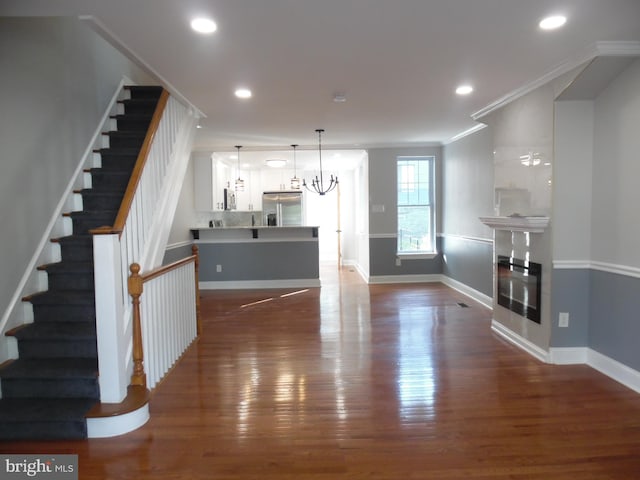 living room featuring crown molding, dark hardwood / wood-style floors, and a notable chandelier