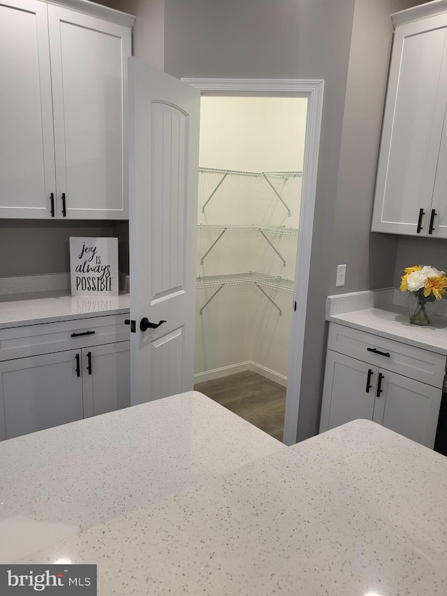 kitchen with white cabinetry, hardwood / wood-style flooring, and light stone countertops