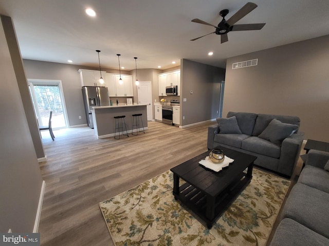 living room with ceiling fan and light wood-type flooring