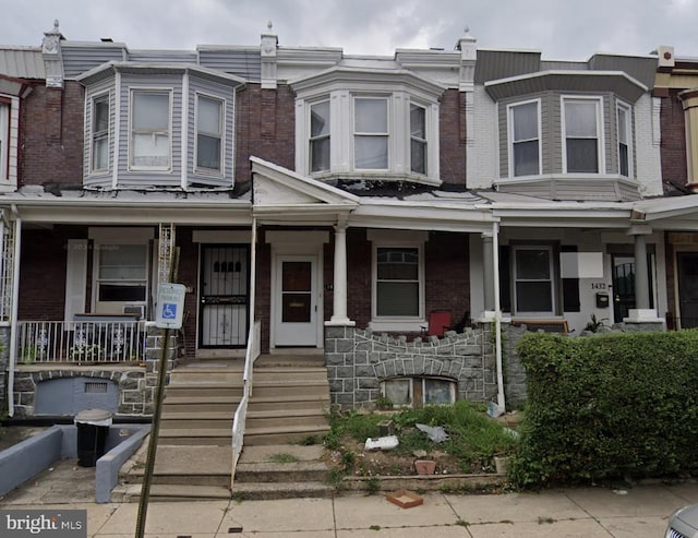 townhome / multi-family property featuring brick siding and a porch