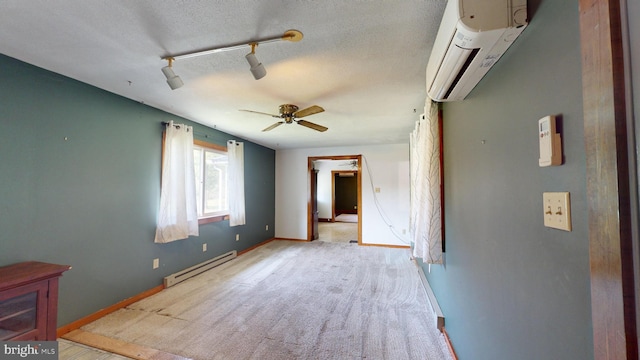 interior space featuring an AC wall unit, track lighting, a baseboard heating unit, a textured ceiling, and baseboards