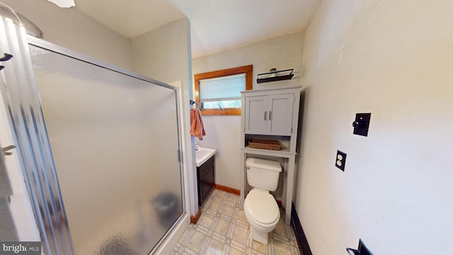 bathroom with a stall shower, toilet, vanity, and baseboards