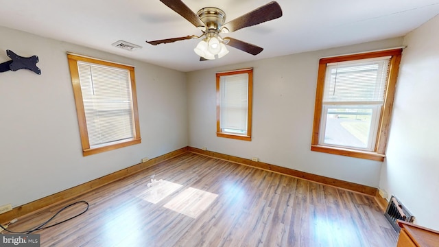 spare room featuring visible vents, a ceiling fan, baseboards, and wood finished floors