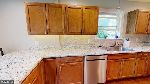 kitchen featuring wood finished floors, a sink, decorative backsplash, dishwasher, and brown cabinets