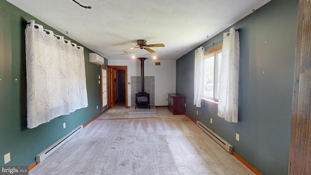 unfurnished living room with baseboards, a wall mounted air conditioner, a baseboard heating unit, and a wood stove