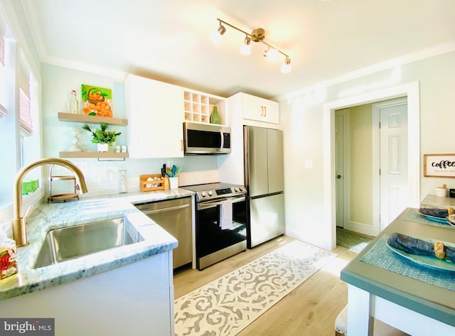 kitchen featuring sink, light stone counters, light hardwood / wood-style flooring, white cabinets, and appliances with stainless steel finishes