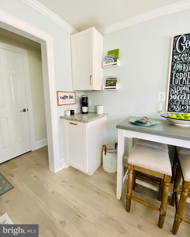 kitchen with light hardwood / wood-style floors, white cabinetry, and ornamental molding