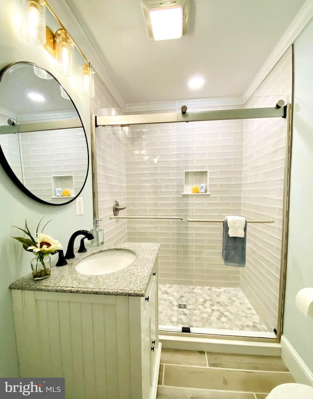 bathroom featuring vanity, an enclosed shower, and crown molding