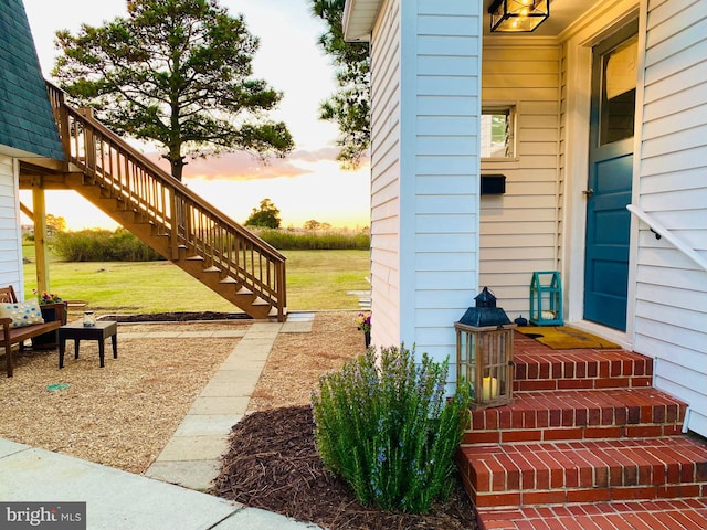 patio terrace at dusk featuring a lawn