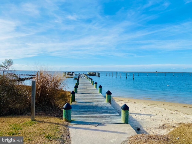 view of dock featuring a beach view and a water view