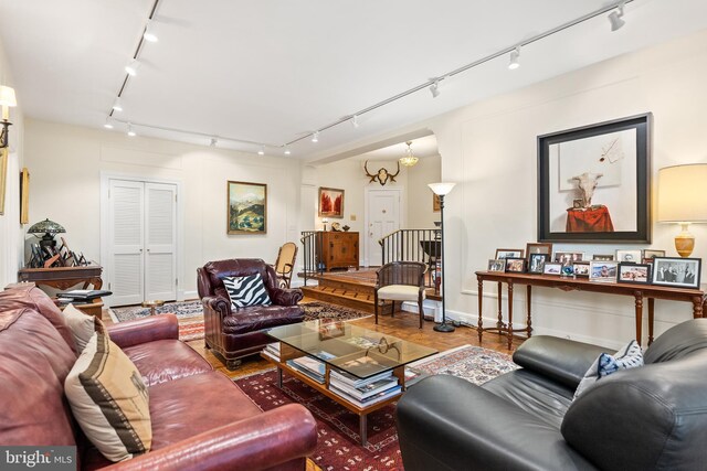 living room with rail lighting, wood-type flooring, and a chandelier