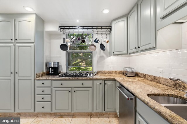 kitchen featuring appliances with stainless steel finishes, tasteful backsplash, light stone counters, and sink