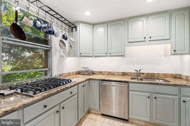 kitchen with appliances with stainless steel finishes, light stone counters, light tile patterned flooring, and sink