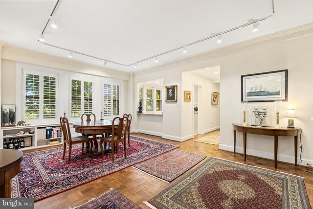 dining space featuring rail lighting and parquet flooring