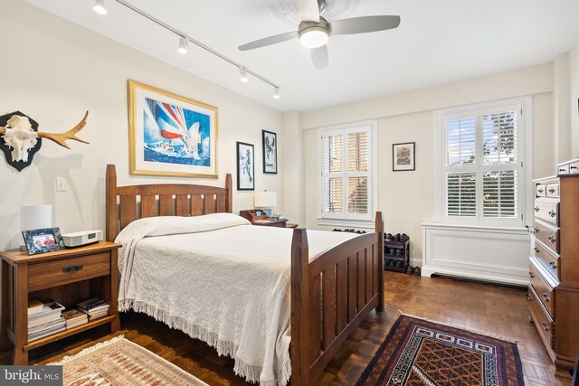 bedroom with dark parquet floors, ceiling fan, and rail lighting