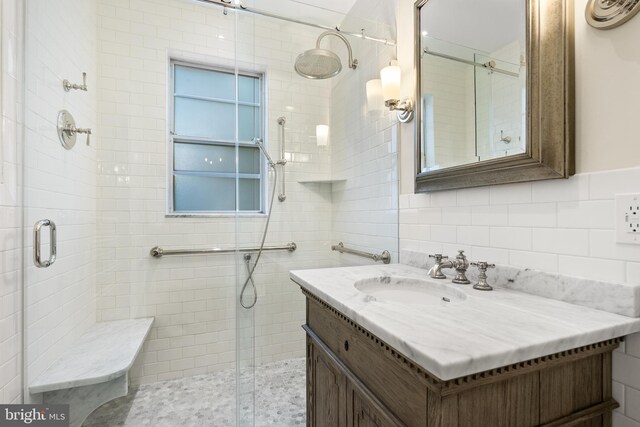 bathroom with vanity, tile walls, and a shower with door