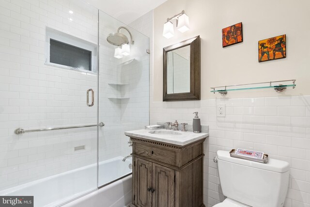 full bathroom featuring vanity, toilet, tile walls, and enclosed tub / shower combo