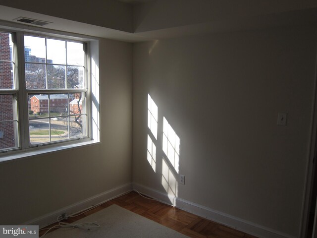 unfurnished room with plenty of natural light and dark parquet floors