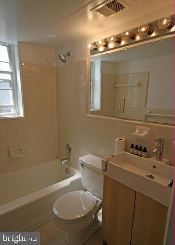 bathroom with toilet, visible vents, tile walls, tasteful backsplash, and washtub / shower combination