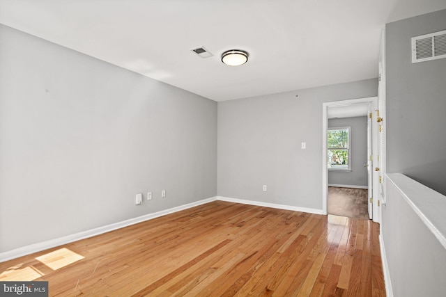 spare room with visible vents, baseboards, and wood finished floors