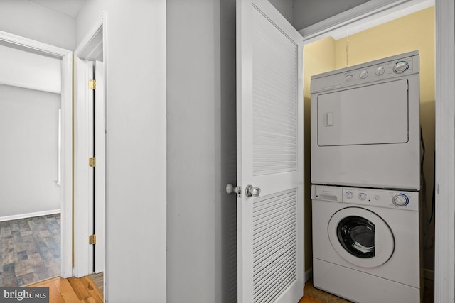 clothes washing area with stacked washer and dryer, laundry area, and wood finished floors