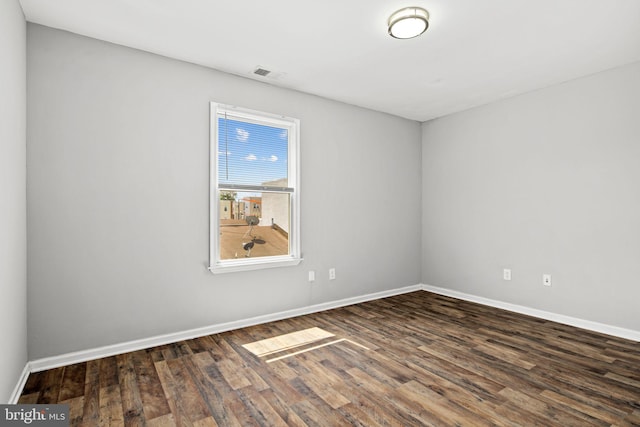 spare room featuring visible vents, baseboards, and dark wood finished floors