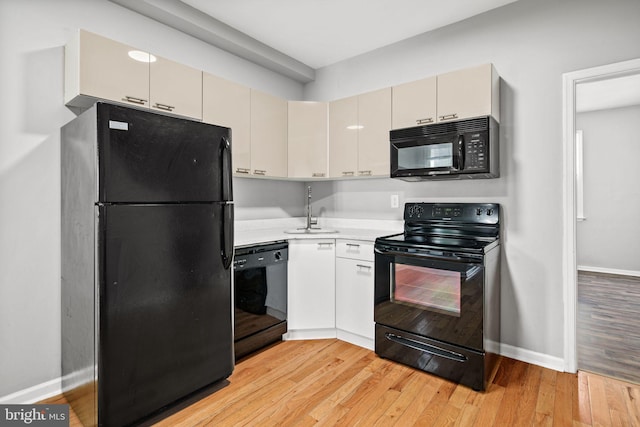 kitchen with black appliances, light hardwood / wood-style floors, and sink