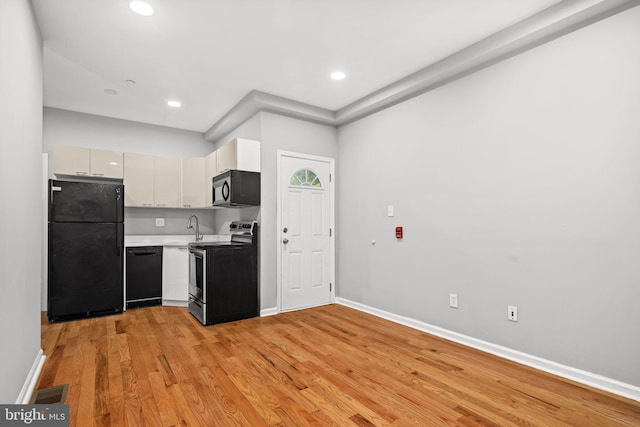 kitchen featuring black appliances, sink, white cabinetry, and light hardwood / wood-style floors