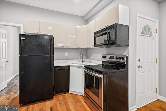 kitchen with black appliances, sink, light hardwood / wood-style flooring, and white cabinets