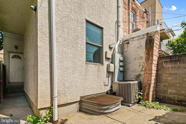 view of side of property featuring a patio, fence, cooling unit, and stucco siding