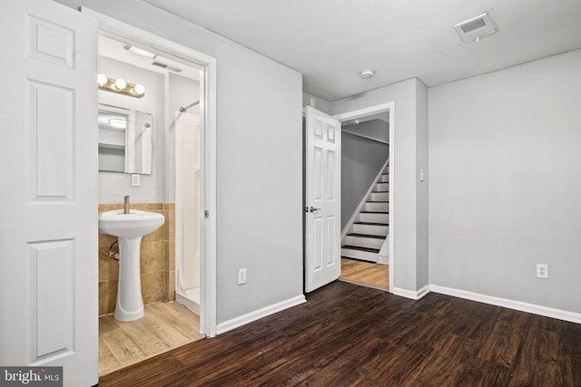 unfurnished bedroom with dark wood-style floors, visible vents, and tile walls