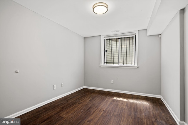 unfurnished room with baseboards and dark wood-style flooring