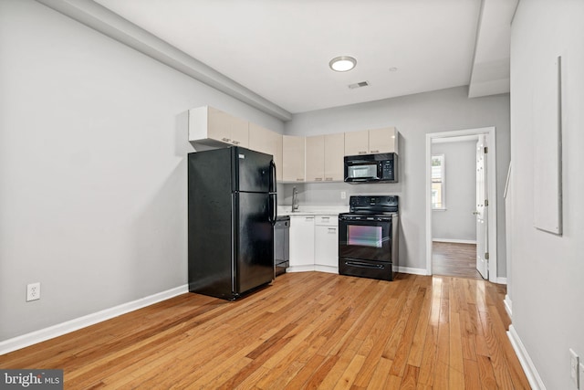 kitchen with black appliances, sink, and light hardwood / wood-style floors