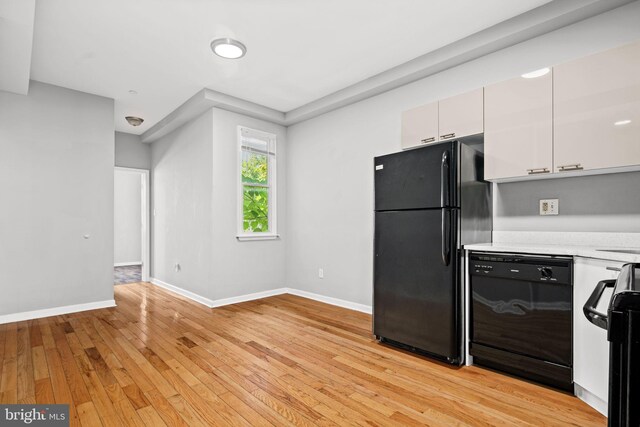 kitchen with black appliances, light hardwood / wood-style flooring, and white cabinets