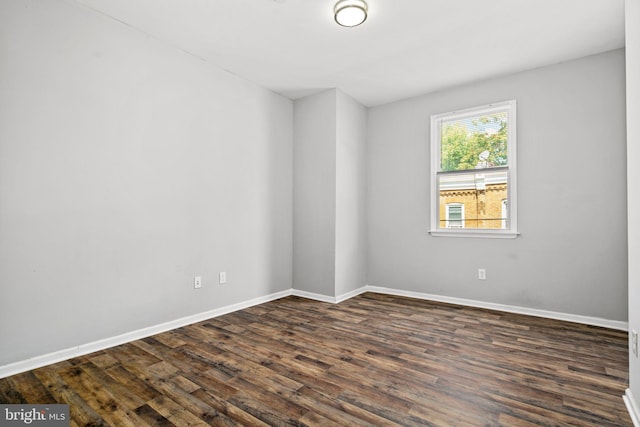 unfurnished room with baseboards and dark wood-style flooring