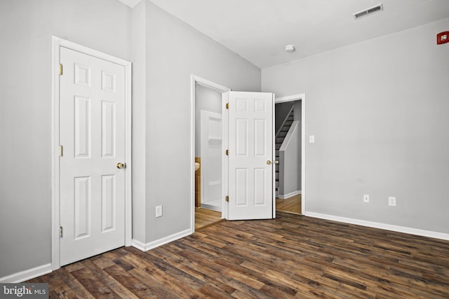 unfurnished bedroom featuring dark wood-type flooring, visible vents, and baseboards