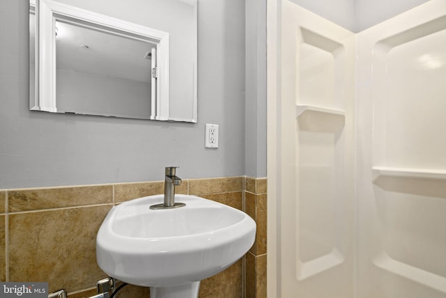 bathroom featuring a sink, a wainscoted wall, and tile walls