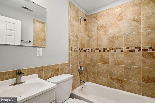 full bathroom with vanity, toilet, tile walls, and tiled shower / bath