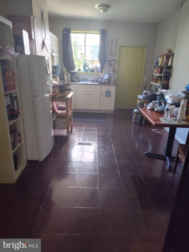 kitchen featuring white cabinets and white fridge