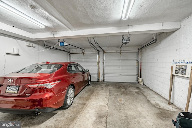 garage with a garage door opener and concrete block wall