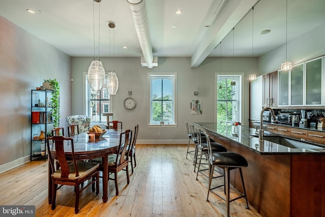 dining space with sink, light wood-type flooring, and a notable chandelier