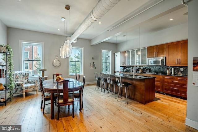 kitchen featuring light wood-style floors, appliances with stainless steel finishes, brown cabinets, and backsplash