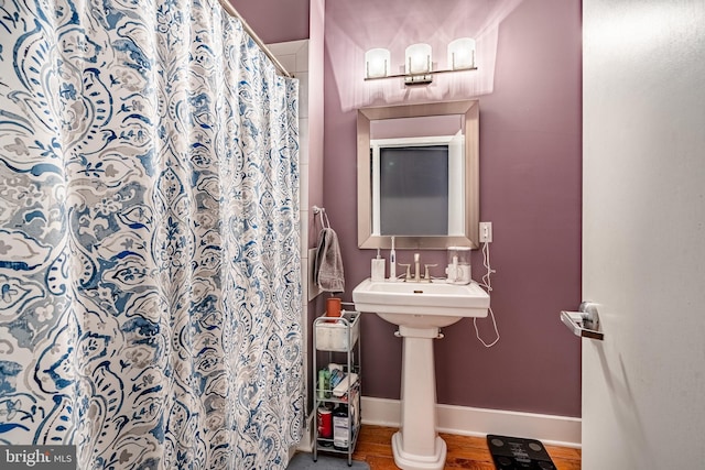 bathroom with a shower with shower curtain, baseboards, and wood finished floors