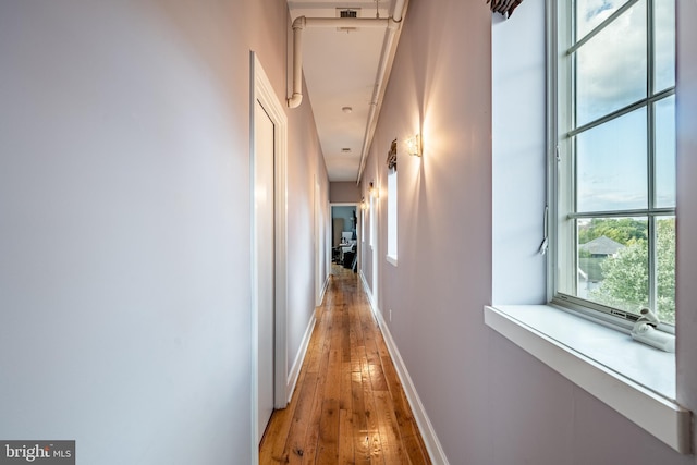 corridor featuring light wood-style flooring and baseboards