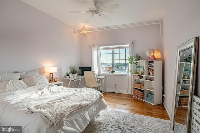 bedroom with a ceiling fan, baseboards, and wood finished floors